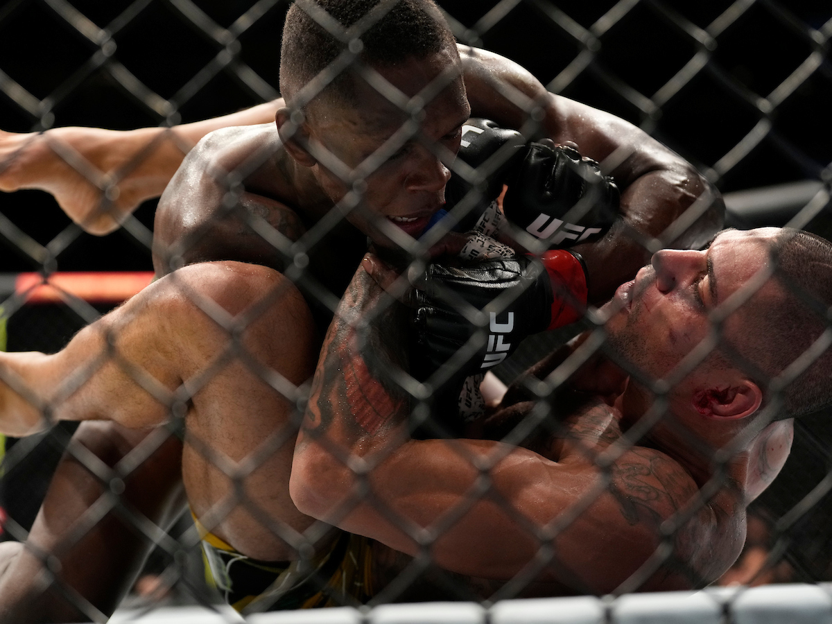Israel Adesanya trabalha no chão por cima de Alex Poatan na disputa pelo título peso-médio no UFC 281.